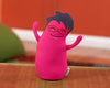 A pink, travel-sized stuffed toy resembling an egg with arms and glasses, set against a blurred background.