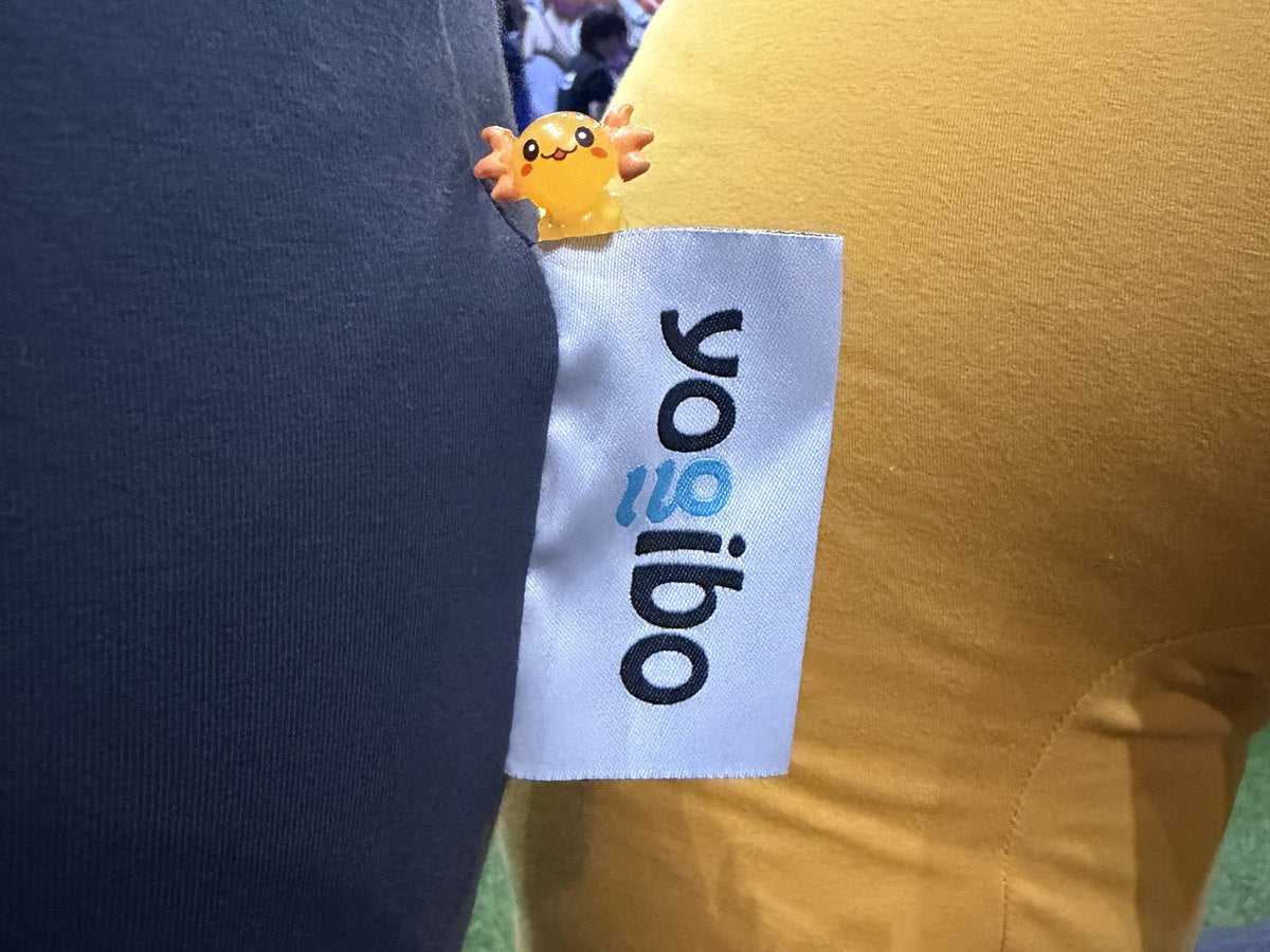 Close-up of the Yogibo tag on a bean bag with a tiny axolotl figure tucked in