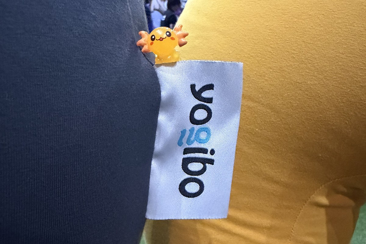 A tiny axolotl figure tucked beside the Yogibo tag on a bean bag at the PAX West booth
