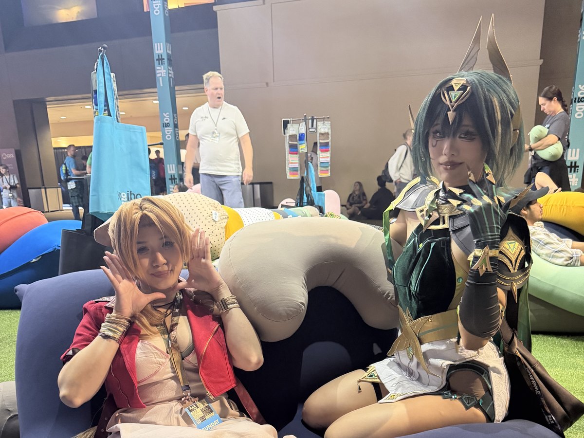 Two cosplayers posing on navy Yogibo bean bags on the green turf lounge
